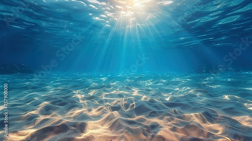 Seabed sand with blue tropical ocean above, empty underwater background with the summer sun shining brightly, creating ripples in the calm sea water © Jennifer