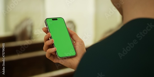 Hand-held smartphone with a green screen in a church interior