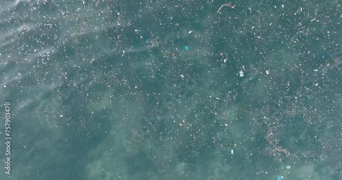 Top down descending drone shot of polluted water filled with plastic trash and dead coral reef in the turqouise tropical water of  Bali Indonesia photo