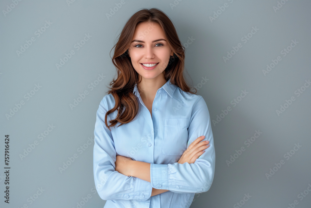 Happy young smiling confident professional business woman wearing blue shirt, pretty stylish female executive looking at camera, standing arms crossed isolated at gray background Happy young smiling confident professional business woman wearing blue shirt, pretty stylish female executive looking at camera, standing arms crossed isolated at gray background