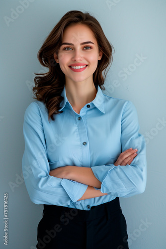Happy young smiling confident professional business woman wearing blue shirt, pretty stylish female executive looking at camera, standing arms crossed isolated at gray background 