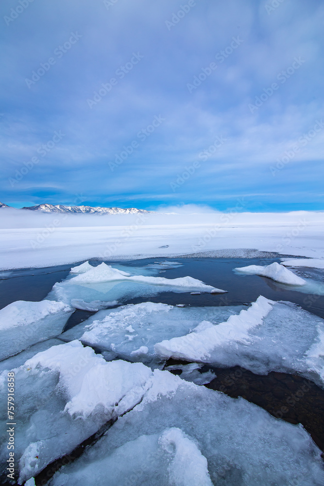 青空の下の氷の湖。湖面の割れた氷。北海道の屈斜路湖。