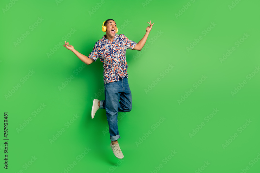 Full length photo of cheerful carefree man dressed stylish summer clothes enjoy music look empty space isolated on green color background Full length photo of cheerful carefree man dressed stylish summer clothes enjoy music look empty space isolated on green color background