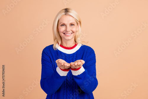 Portrait of grateful satisfied toothy beaming person wear blue pullover arms holding object empty space isolated on beige color background