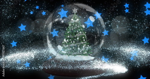 Shooting star over christmas tree in a snow globe against multiple blue stars icons floating