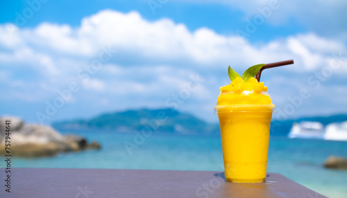 Smoothie made from fresh mango fruits against the backdrop of a seascape. Fruit and yoghurt ice cream decorated with leaves. Glass of tropical dessert close-up.