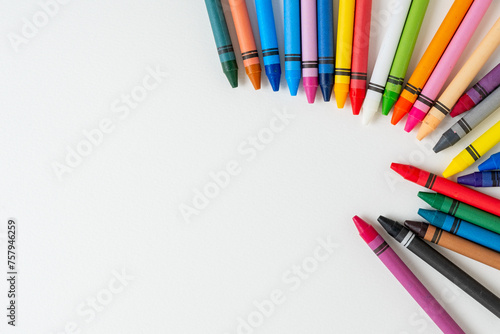 Large set of multi-colored children's wax crayons on a white background with space for text on the left side