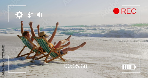 Image of a side view of a young Caucasian couple in deckchairs, seen on a screen of a digital camera