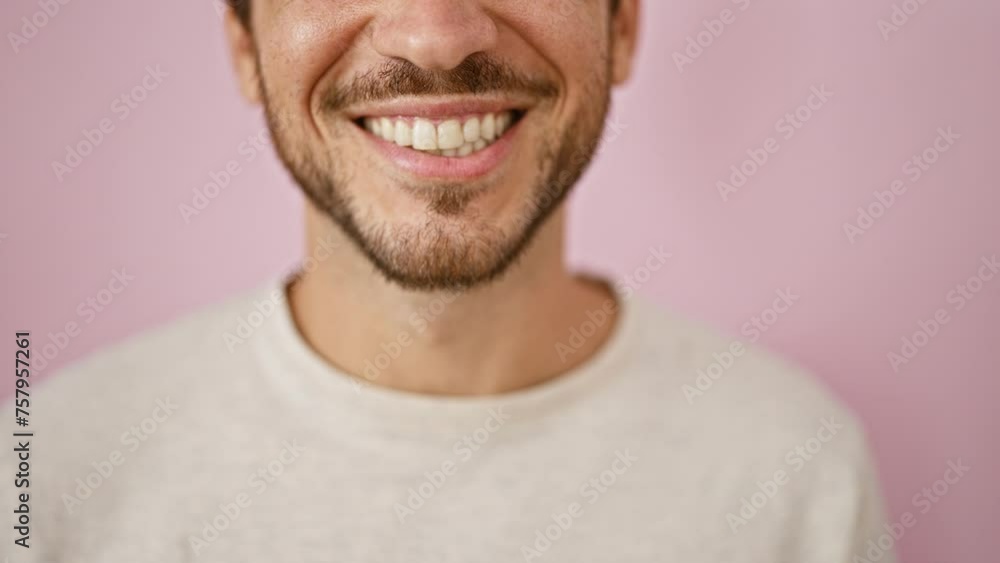 A young hispanic man with a beard wearing a white shirt presents varied expressions in a portrait series against a pink isolated background. A young hispanic man with a beard wearing a white shirt presents varied expressions in a portrait series against a pink isolated background.