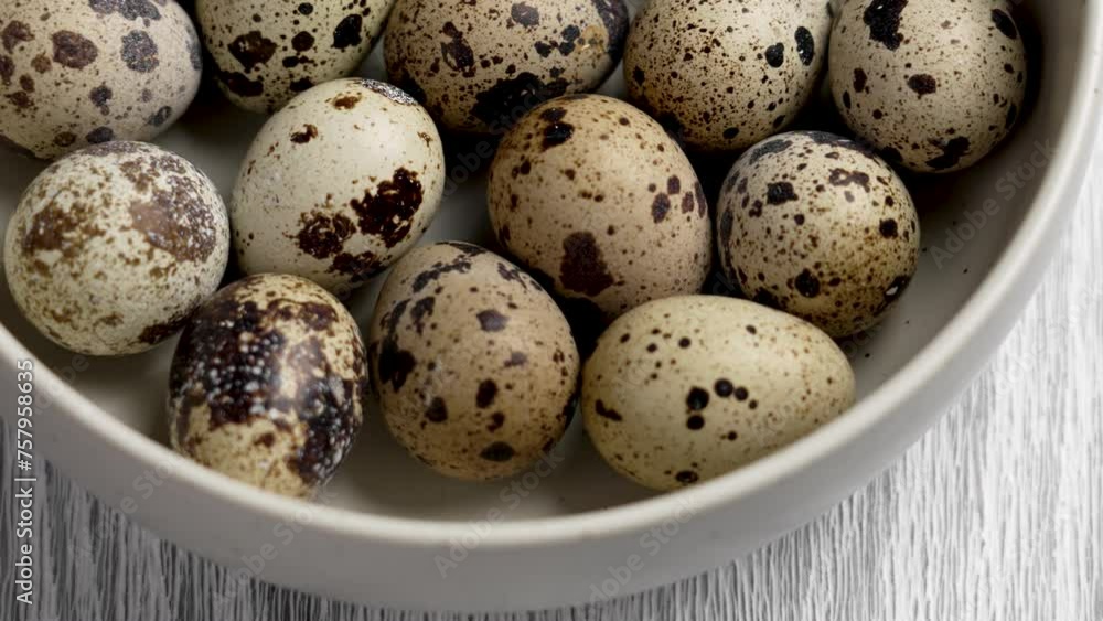 Group of raw fresh quail eggs in a ceramic bowl on a rustic board. Healthy Easter eating. Rotation Group of raw fresh quail eggs in a ceramic bowl on a rustic board. Healthy Easter eating. Rotation