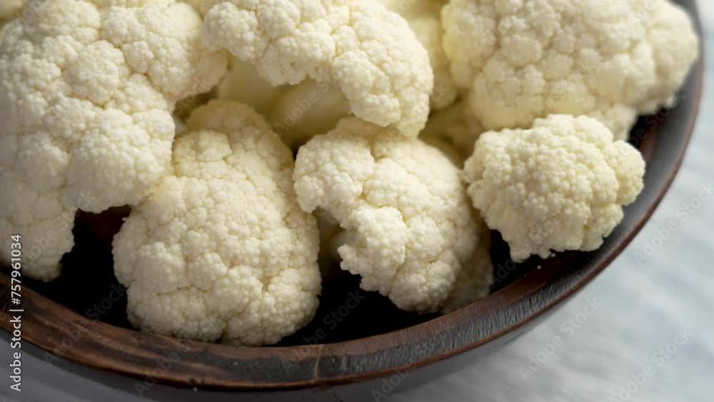 Fresh white cauliflower cut in pieces in rustic wooden bowl. Healthy organic farm veggies. Rotation Fresh white cauliflower cut in pieces in rustic wooden bowl. Healthy organic farm veggies. Rotation