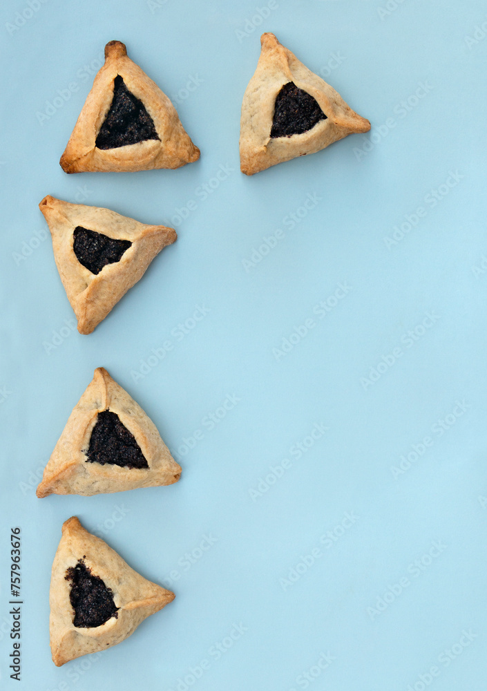 Triangular cookies with poppy seeds ( hamantasch or aman ears ) for jewish holiday of purim celebration on blue background with space for text. Top view, flat lay - obrazy, fototapety, plakaty 