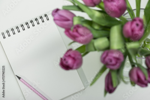 Lilac tulips and an open notepad on the table. Elegant female workplace.Selective focus. Concept for congratulations on Valentine's Day, Birthday, Mother's Day and Women's Day.