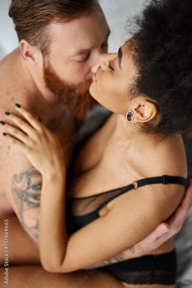 top view of multicultural sexy couple embracing and kissing in bedroom, seduction and passion top view of multicultural sexy couple embracing and kissing in bedroom, seduction and passion