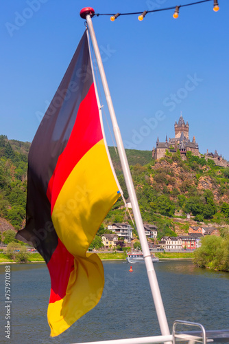 German flag flutters against the background of Reichsburg castle, Cochem, Germany