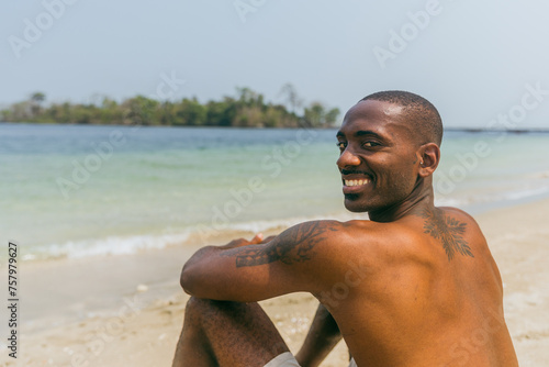 A smiling African man enjoys vacation at a paradise beach