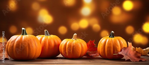 Vibrant Three Pumpkins Surrounded by Colorful Autumn Leaves on a Rustic Wooden Table