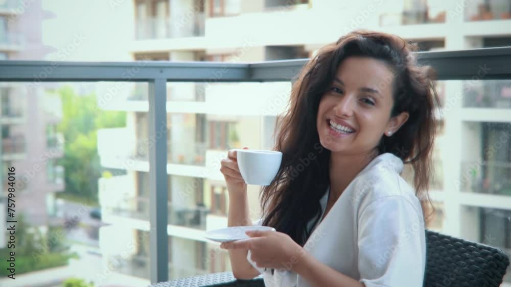 Cheerful young lady smiling while looking at camera holding cup of tea in hands Cheerful young lady smiling while looking at camera holding cup of tea in hands