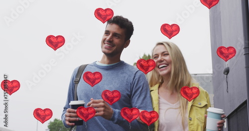Image of heart icons floating over happy caucasian couple walking and drinking takeaway coffee