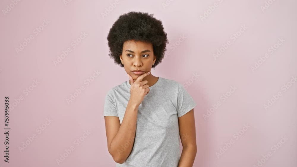 Pensive african american woman in pink tee, focused, finger on chin digesting doubt, lost in thought, standing isolated against pink background Pensive african american woman in pink tee, focused, finger on chin digesting doubt, lost in thought, standing isolated against pink background