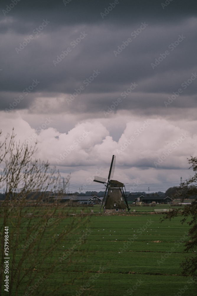 Landscape with ancient windmills in the Netherlands in gloomy spring weather. Stormy day over Dutch village of Streefkerk, Alblasserwaard, South Holland Landscape with ancient windmills in the Netherlands in gloomy spring weather. Stormy day over Dutch village of Streefkerk, Alblasserwaard, South Holland