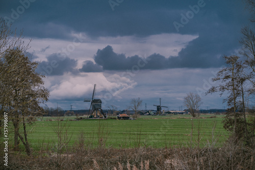Landscape with ancient windmills in the Netherlands in gloomy spring weather. Stormy day over Dutch village of Streefkerk, Alblasserwaard, South Holland
