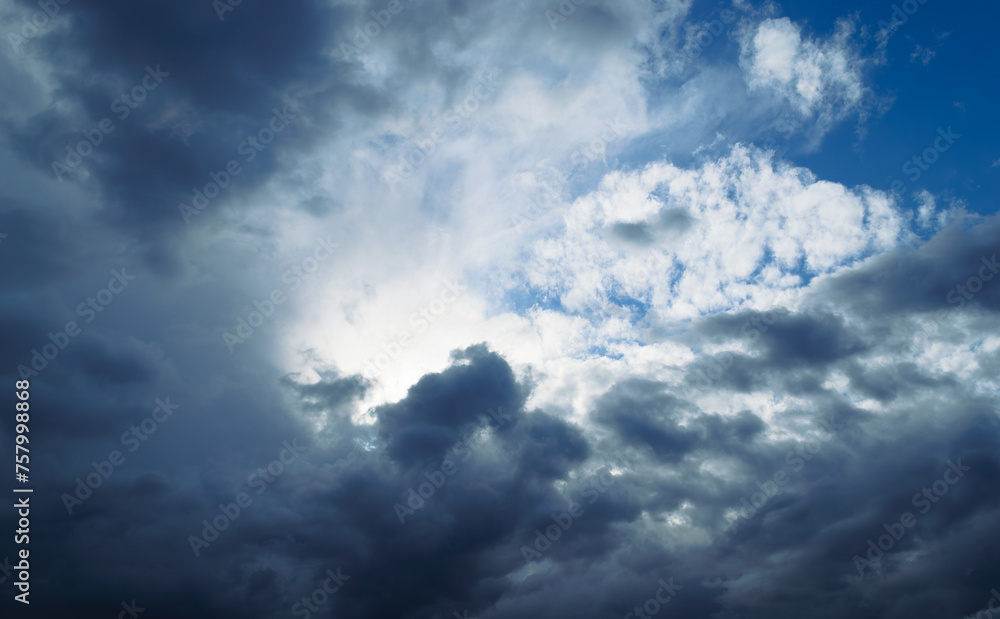 The sun is shining behind the rain cumulus clouds high in the sky