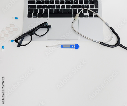 Top view of computer, stethoscope, thermometer, eyeglases and pills photo
