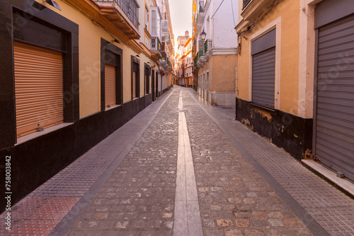 Old narrow traditional street in Cadiz at dawn.