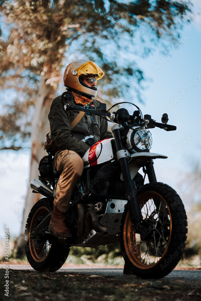 Chico con barba con atuendo de motorista posando con su moto y su cámara Chico con barba con atuendo de motorista posando con su moto y su cámara