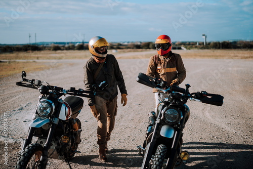Dos amigos hombres con motos tipo scrambler en area desertica photo