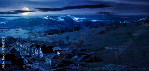 Obraz na płótnie alpine countryside ant night. village in the valley and distant mountain range with snow capped tops in full moon light w salonie