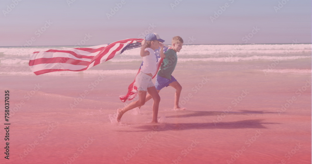 Fototapeta premium Image of smiling caucasian siblings with american flags running at beach