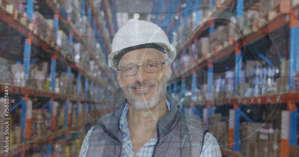 Composite image of surveillance camera over caucasian male senior supervisor smiling at warehouse Composite image of surveillance camera over caucasian male senior supervisor smiling at warehouse