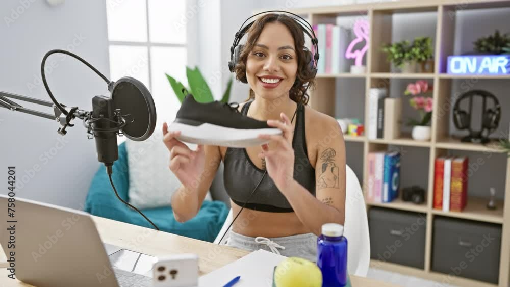 Smiling woman presents sneakers in a modern radio studio with microphone and headphones. Smiling woman presents sneakers in a modern radio studio with microphone and headphones.