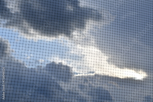Bright Clouds Over Mesh Net Fence