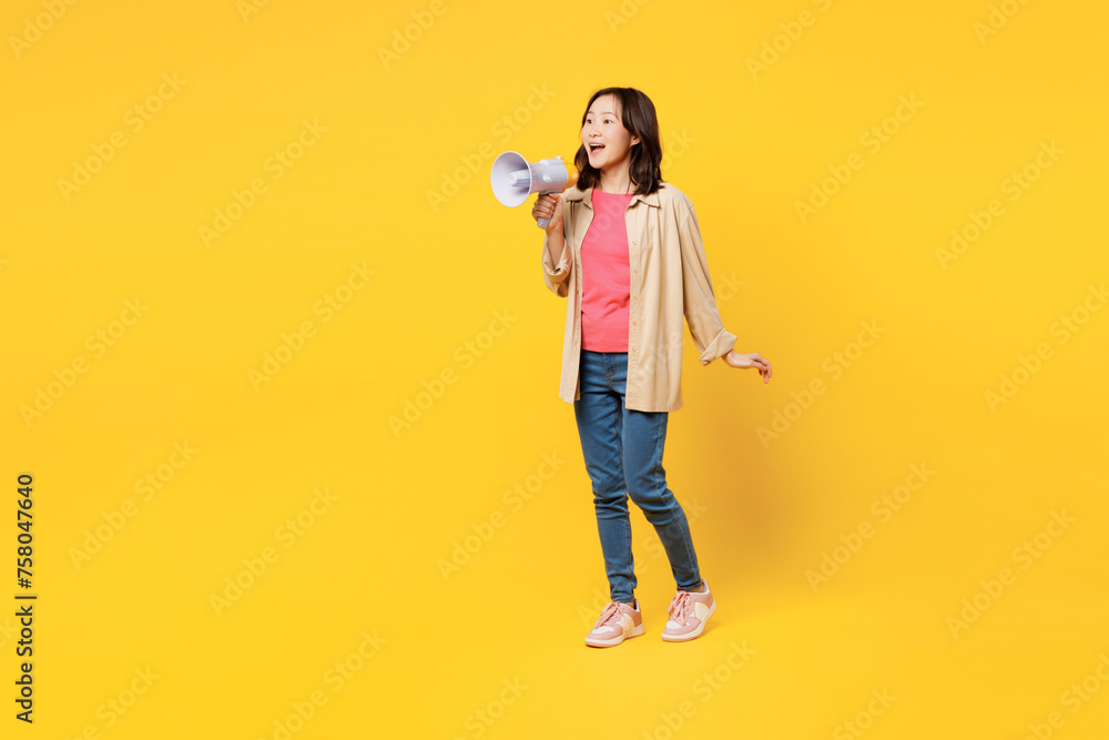 Full body young woman of Asian ethnicity wear pink t-shirt beige shirt casual clothes hold megaphone scream announces discounts sale Hurry up isolated on plain yellow background. Lifestyle portrait. Full body young woman of Asian ethnicity wear pink t-shirt beige shirt casual clothes hold megaphone scream announces discounts sale Hurry up isolated on plain yellow background. Lifestyle portrait.