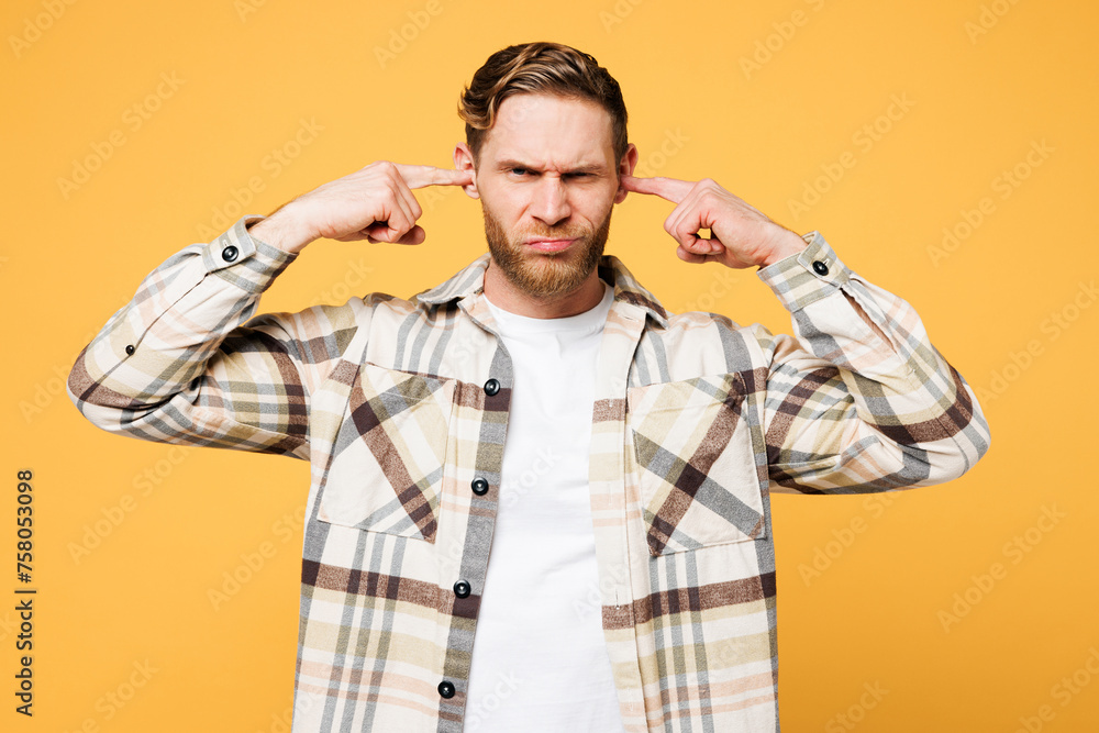 Young sad mad Caucasian man he wear brown shirt casual clothes cover ears with hands fingers do not want to listen scream isolated on plain yellow orange background studio portrait. Lifestyle concept. Young sad mad Caucasian man he wear brown shirt casual clothes cover ears with hands fingers do not want to listen scream isolated on plain yellow orange background studio portrait. Lifestyle concept.