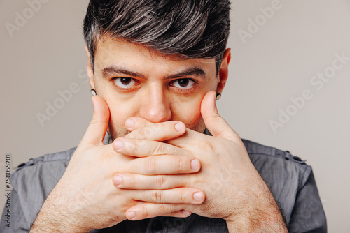 Young man covering mouth with hands. Emotional concept. Diet concept