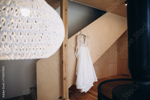 Wedding. Details. The bride's white dress weighs down the wooden staircase in the house photo