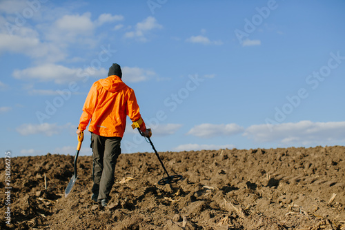 A man with an electronic metal detector in the field. Copyspace