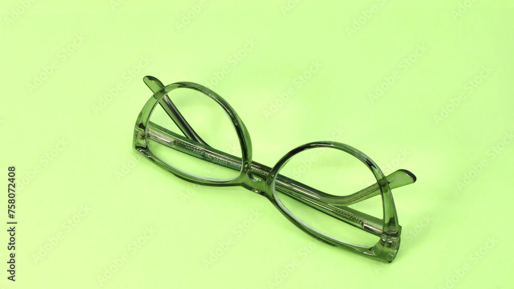 Pair of glasses with a green transparent frame isolated on a plain light green background. Copy space. Pair of glasses with a green transparent frame isolated on a plain light green background. Copy space.