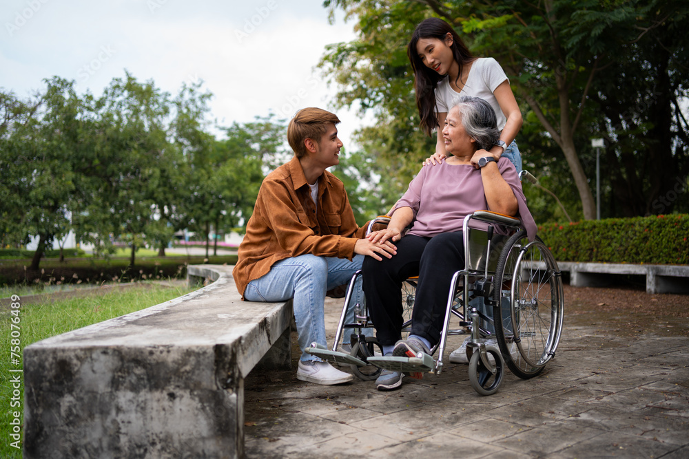 Obraz premium Asian careful caregiver or nurse taking care of the patient in a wheelchair. Concept of a happy retirement with care from a caregiver and Savings and senior health insurance, a Happy Family