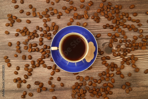 Close-up and top view of hot black coffee in blue coffee cup and roasted Thai coffee beans on wooden background. photo