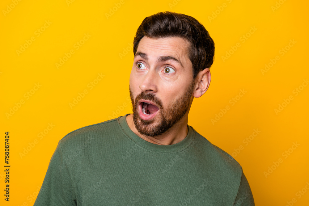 Photo of positive impressed guy dressed green t-shirt looking empty space isolated yellow color background Photo of positive impressed guy dressed green t-shirt looking empty space isolated yellow color background