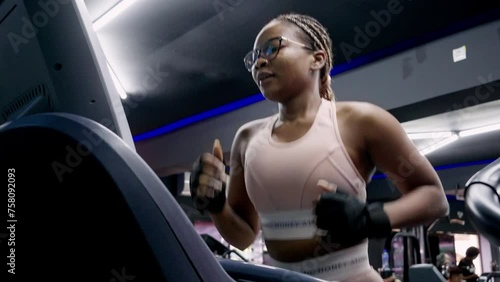Young black woman in the gym running on the treadmill
