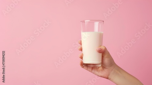 Side view of hand holding milk glass on light pastel background with ample space for text placement