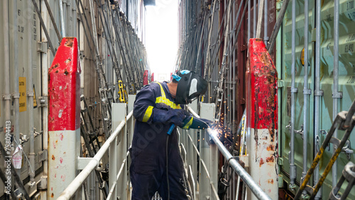 Seaman crew member fitter welder of cargo vessel is repairing ship structure lashing bridge by welding of new pipes dressed with proper ppe