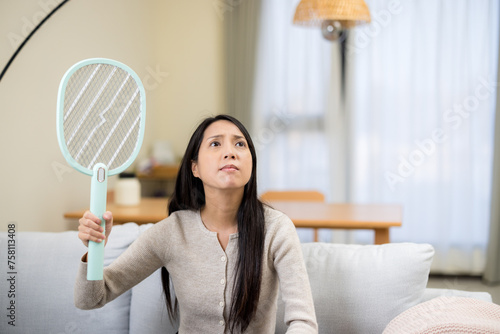 Woman use mosquito swatter at home photo