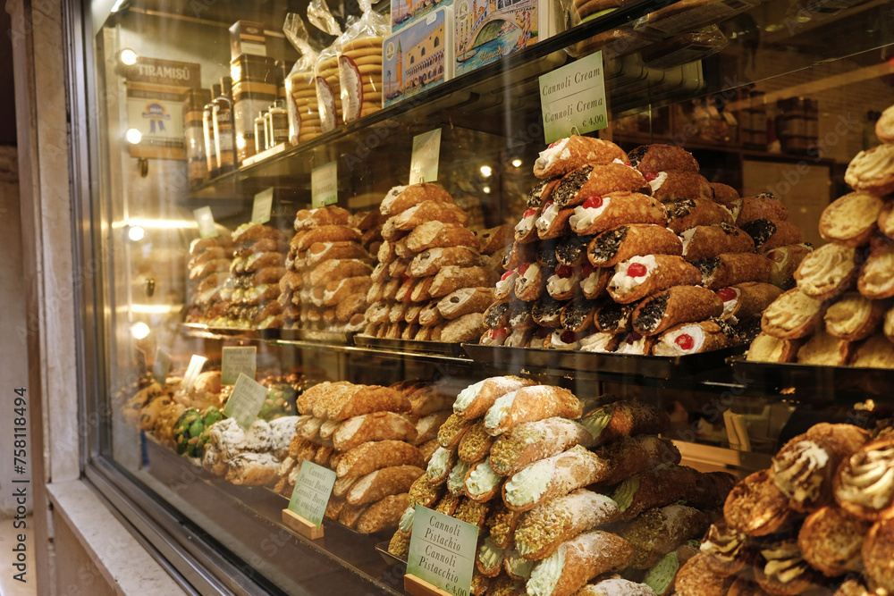 Cannoli with different fillings, traditional Italian dessert, pastries in window display in Venice, Italy. Traditional dessert piles with price tags at confectionery shop.